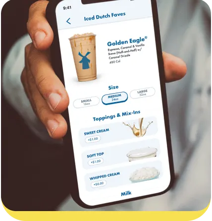 Hand holding phone displaying Dutch Bros coffee app with Golden Eagle drink options and topping selections