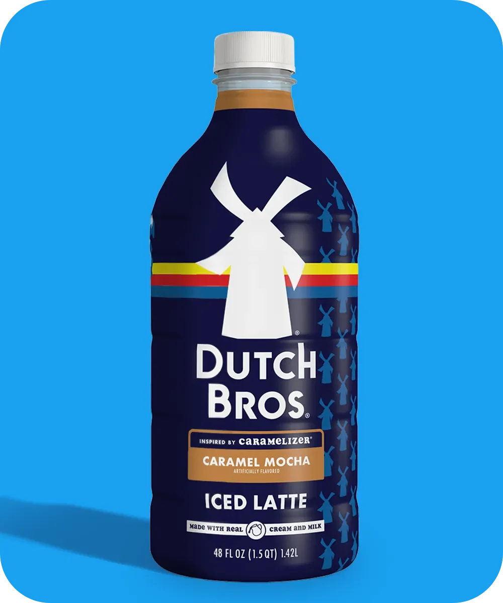 Bottle of Dutch Bros Caramel Mocha Iced Latte with windmill logo on navy blue packaging against bright blue background.